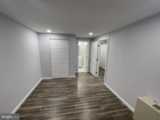 unfurnished bedroom featuring ensuite bath, a closet, and dark hardwood / wood-style floors