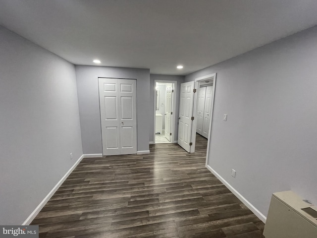 unfurnished bedroom featuring baseboards, dark wood-style floors, ensuite bathroom, and recessed lighting