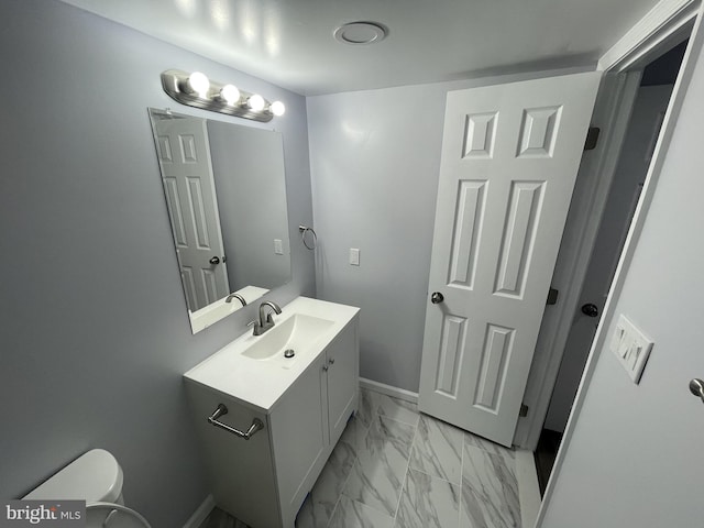 half bath featuring marble finish floor, baseboards, toilet, and vanity