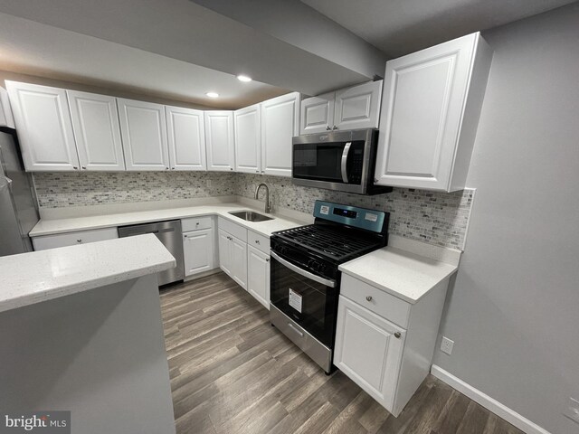 kitchen with decorative backsplash, white cabinets, stainless steel appliances, dark hardwood / wood-style floors, and sink