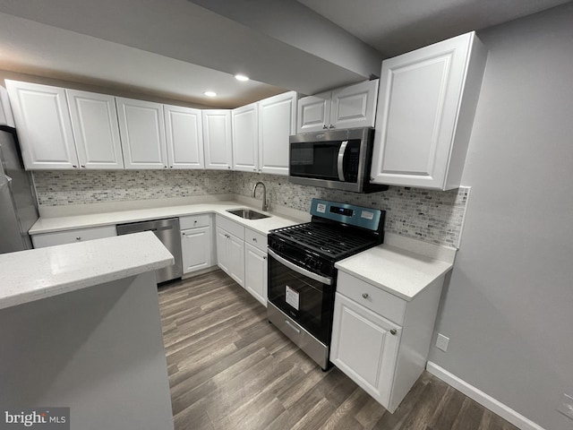 kitchen featuring white cabinets, wood finished floors, a sink, and stainless steel appliances