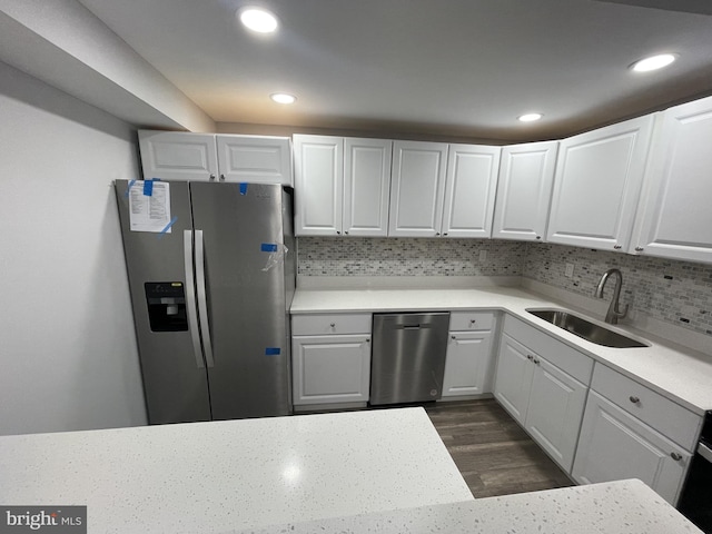 kitchen with backsplash, stainless steel appliances, white cabinetry, and sink