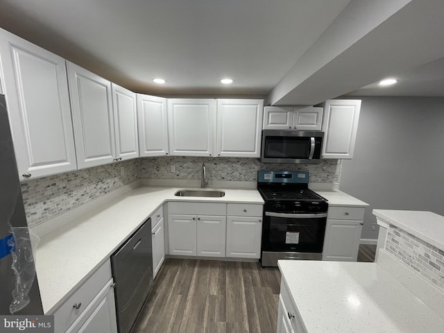 kitchen with tasteful backsplash, stainless steel appliances, dark wood finished floors, a sink, and white cabinets