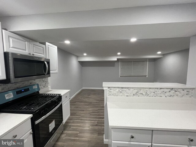 kitchen featuring dark hardwood / wood-style floors, white cabinetry, kitchen peninsula, stainless steel appliances, and backsplash