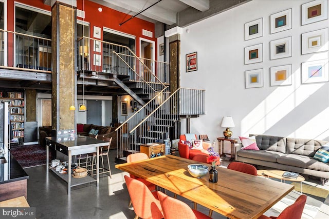 dining room featuring a towering ceiling and concrete floors