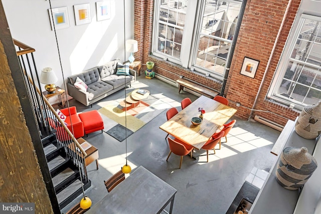 living room with brick wall, a towering ceiling, and concrete floors