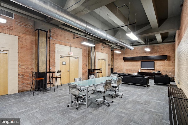 playroom with beam ceiling, a high ceiling, carpet flooring, and brick wall