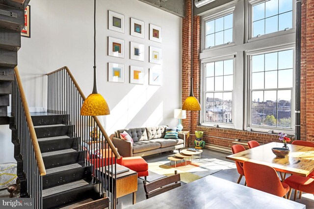 living room featuring a high ceiling and brick wall