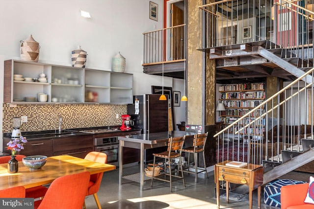 interior space featuring stainless steel appliances, backsplash, sink, and concrete floors