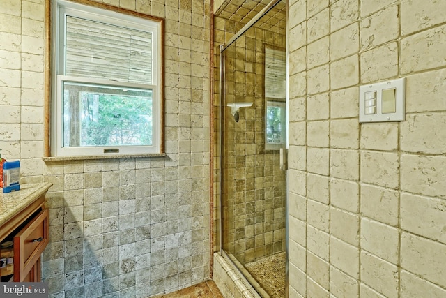 bathroom featuring vanity, brick wall, and a shower with shower door