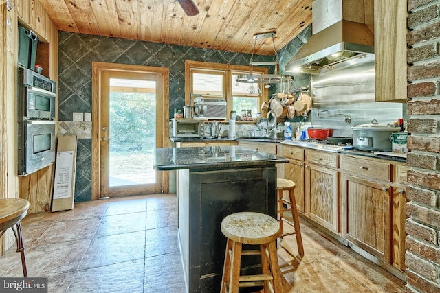 kitchen featuring a breakfast bar area, wall chimney exhaust hood, wood ceiling, and a center island