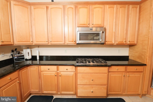 kitchen with dark stone countertops, light tile patterned floors, and stainless steel appliances