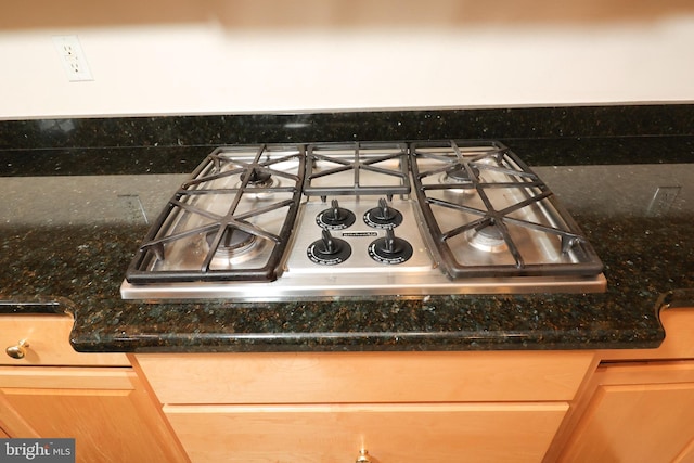 room details featuring stainless steel gas stovetop, light brown cabinetry, dark stone counters, and backsplash