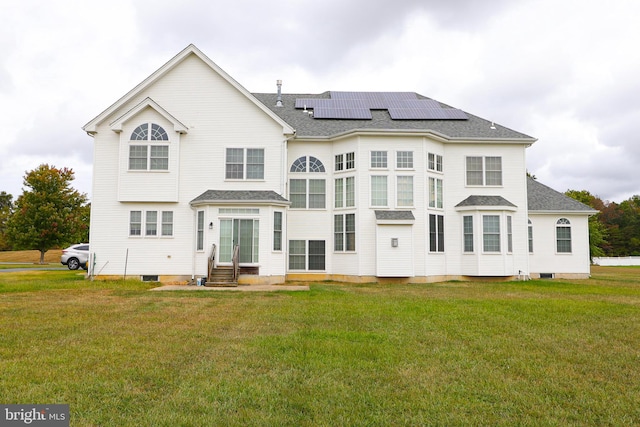 rear view of house featuring a yard and solar panels