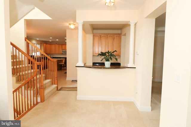 hallway with decorative columns and light colored carpet