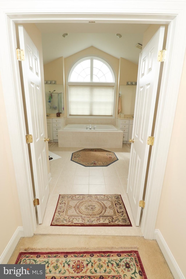 bathroom featuring vaulted ceiling, a tub, and tile patterned floors