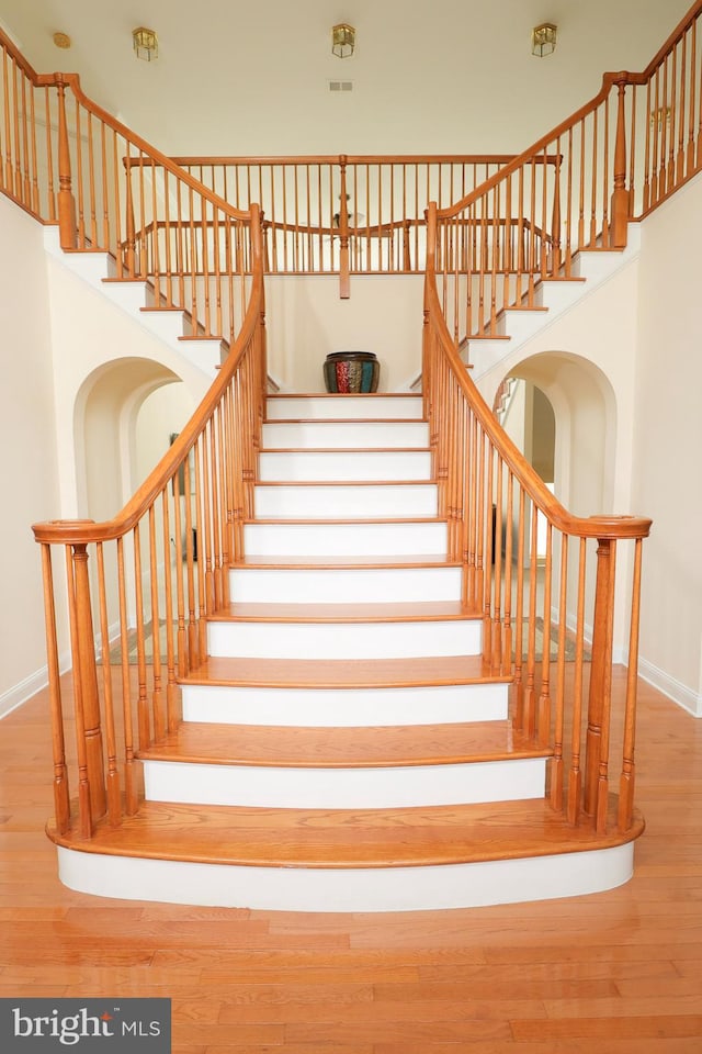 stairway with a towering ceiling and hardwood / wood-style flooring