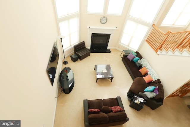 living room featuring a towering ceiling, carpet, and a premium fireplace