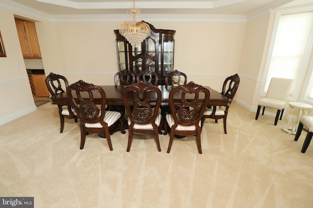 dining area with a notable chandelier, a tray ceiling, light colored carpet, and crown molding