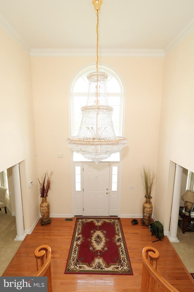 entryway with hardwood / wood-style flooring, crown molding, and a chandelier