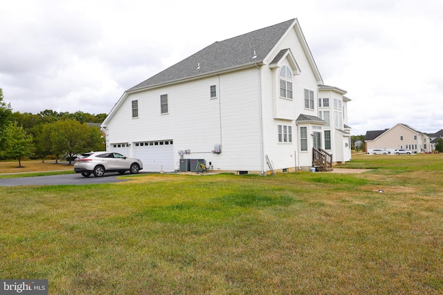 view of side of property featuring cooling unit, a yard, and a garage