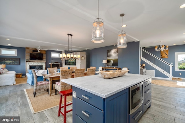 kitchen with decorative light fixtures, a fireplace, a center island, and a breakfast bar