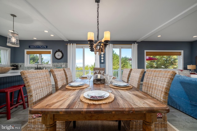 dining area featuring hardwood / wood-style floors, a chandelier, beam ceiling, and a wealth of natural light