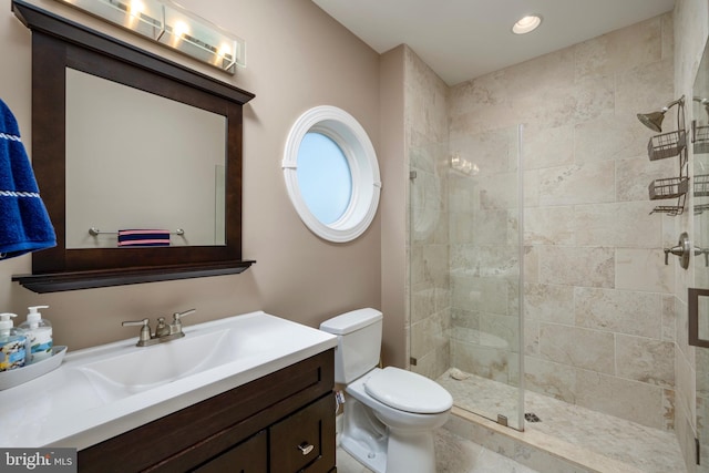 bathroom featuring vanity, a shower with shower door, and toilet