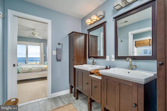 bathroom with a water view, vanity, and ceiling fan