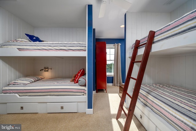 carpeted bedroom with wood walls and ceiling fan