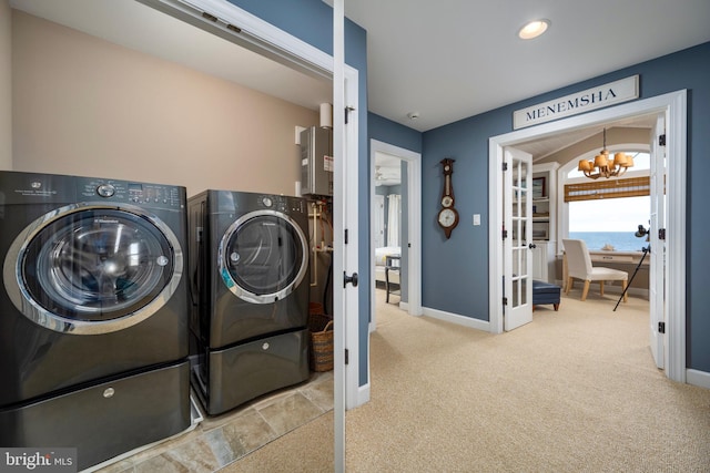 washroom featuring a chandelier, light colored carpet, and separate washer and dryer