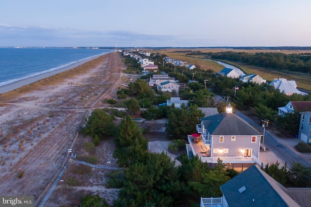 aerial view at dusk with a water view and a beach view