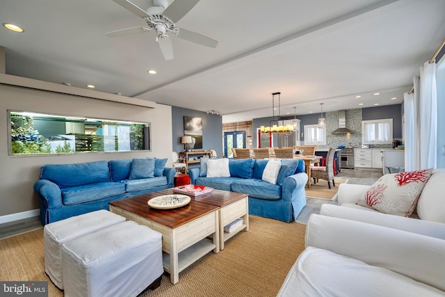 living room featuring ceiling fan with notable chandelier and light wood-type flooring