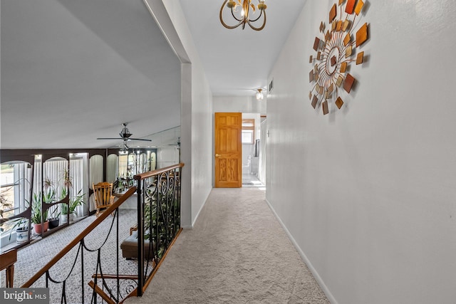 hallway featuring a notable chandelier and carpet flooring