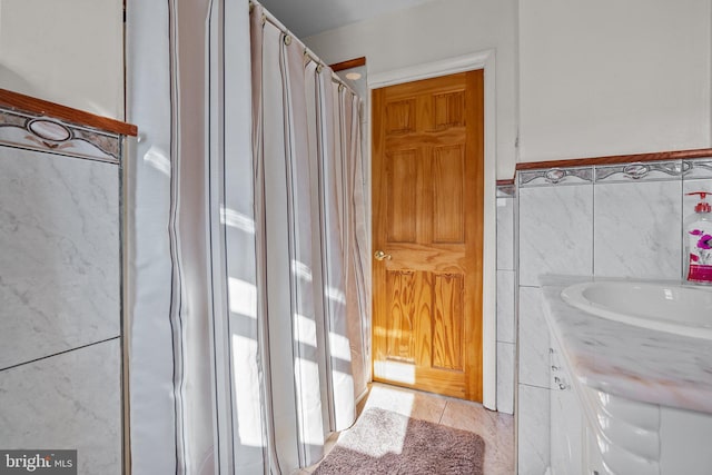 bathroom with vanity, a shower with shower curtain, tile patterned floors, and tile walls