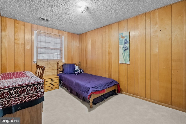 carpeted bedroom with a textured ceiling and wooden walls