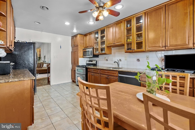 kitchen with sink, light stone countertops, stainless steel appliances, and tasteful backsplash