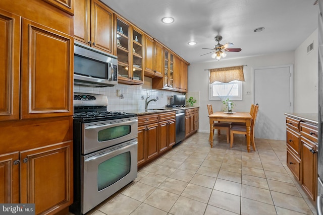 kitchen featuring stainless steel appliances, sink, tasteful backsplash, light tile patterned floors, and ceiling fan