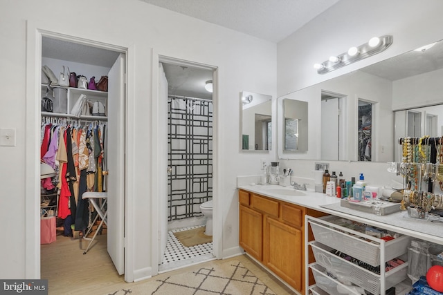 bathroom featuring wood-type flooring, a textured ceiling, vanity, and toilet