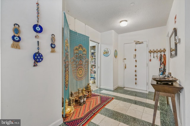 foyer with a textured ceiling and light tile patterned floors