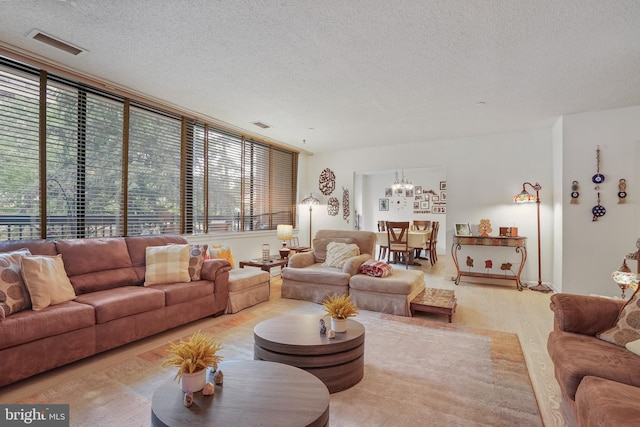 living room featuring an inviting chandelier, a textured ceiling, and a wall of windows