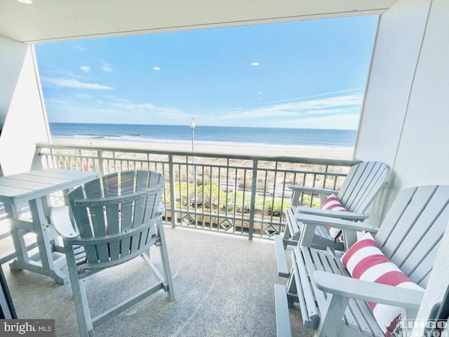 balcony featuring a view of the beach and a water view