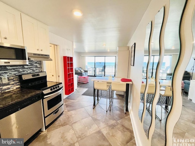 kitchen with appliances with stainless steel finishes, light tile patterned floors, tasteful backsplash, and white cabinetry