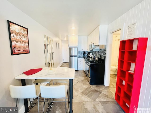 kitchen with stainless steel appliances, decorative backsplash, and white cabinetry