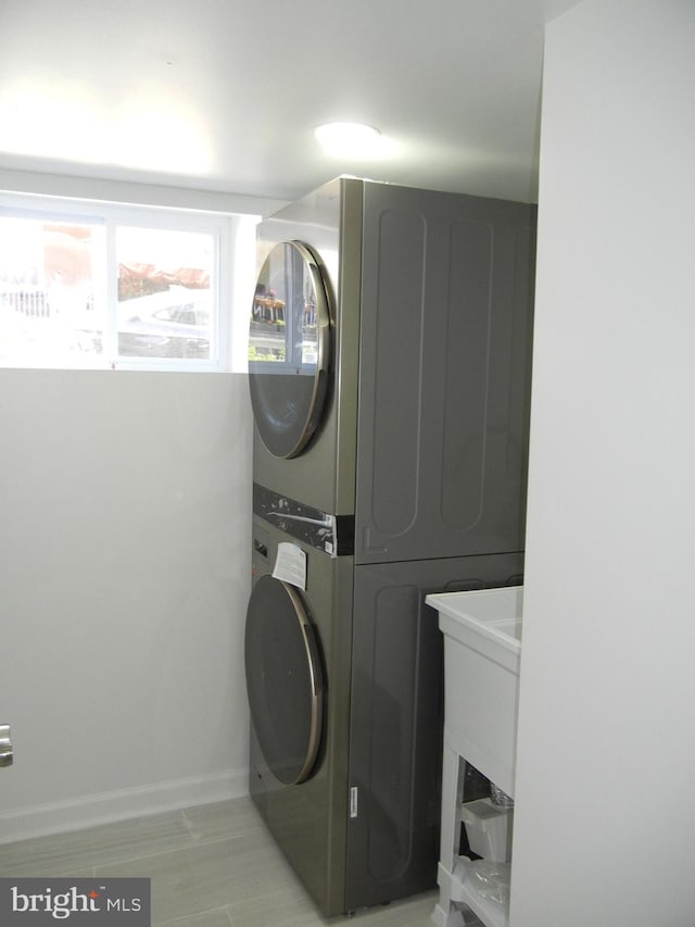 clothes washing area with light wood-type flooring and stacked washing maching and dryer