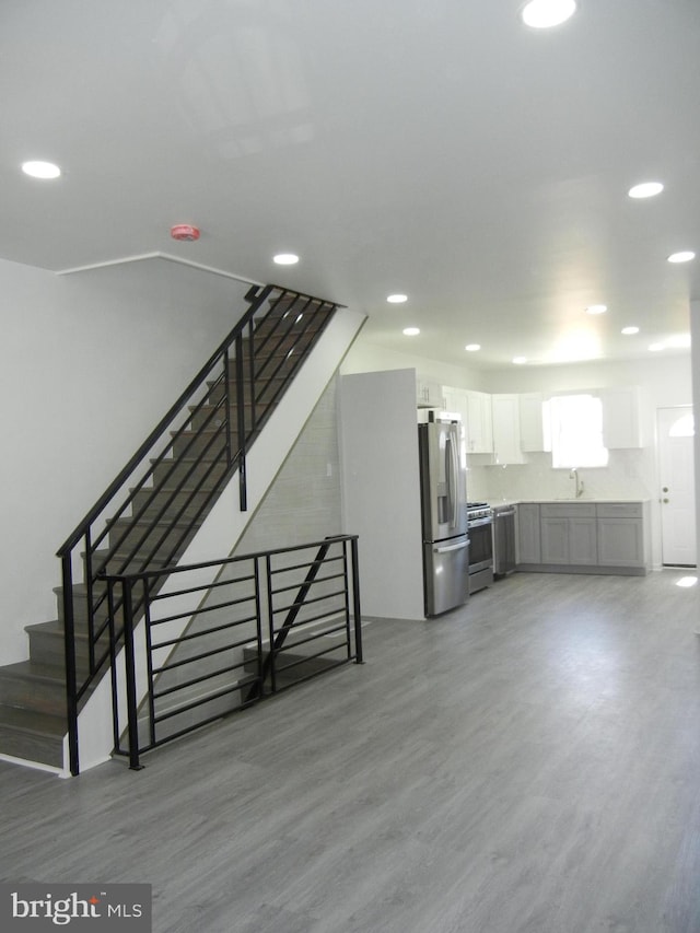 staircase featuring wood-type flooring and sink