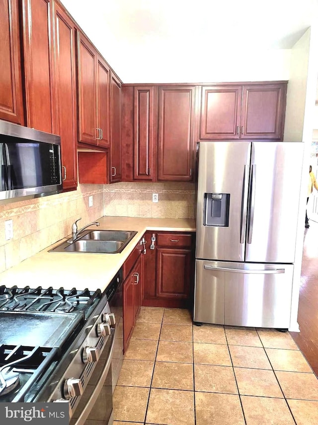 kitchen featuring stainless steel appliances, light tile patterned floors, tasteful backsplash, and sink