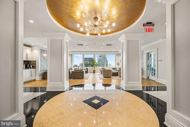 interior space with a tray ceiling, dark hardwood / wood-style floors, and ornate columns