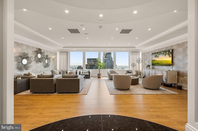 living room with crown molding, a tray ceiling, and light hardwood / wood-style flooring