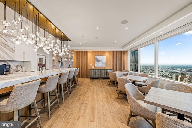 dining area featuring a healthy amount of sunlight, sink, a chandelier, and light hardwood / wood-style flooring